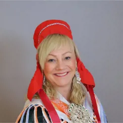 En person som har på seg et rødt og hvitt hodeplagg og smiler