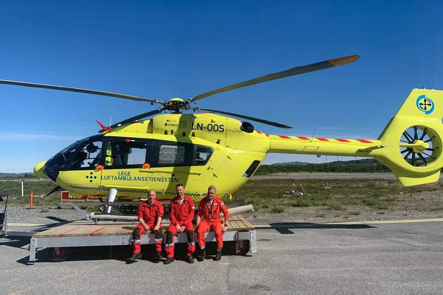 En gruppe mennesker foran et gult helikopter