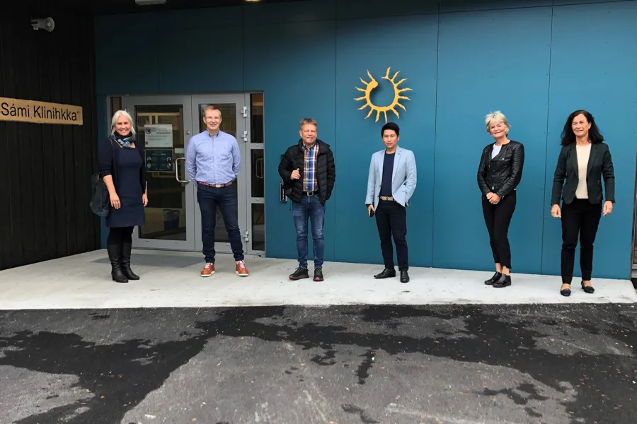En gruppe mennesker som står foran en blå bygning