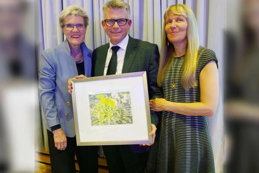Tre personer holder et kunstverk