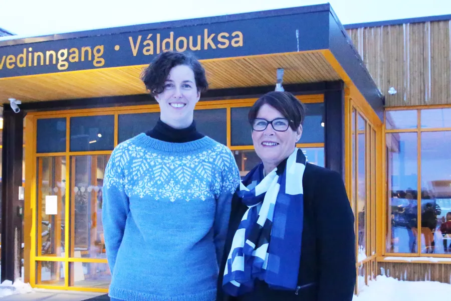 Et par menn som står foran en bygning med et skilt
